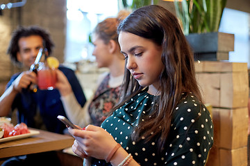 Image showing woman with smartphone and friends at restaurant