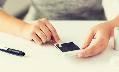 Image showing close up of woman with smartphone doing blood test