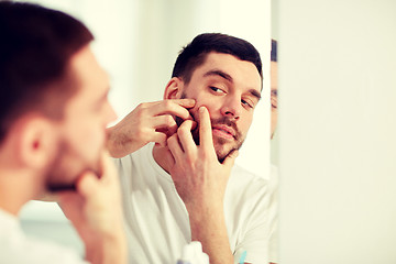 Image showing man squeezing pimple at bathroom mirror