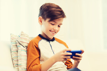 Image showing boy with smartphone texting or playing at home