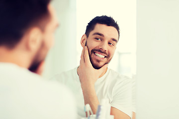 Image showing happy young man looking to mirror at home bathroom