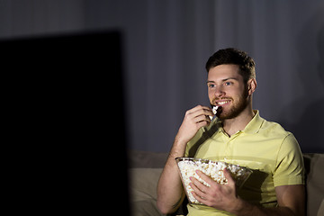 Image showing happy man with popcorn watching tv at night