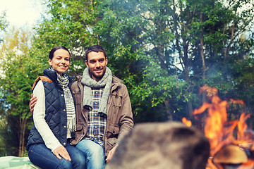 Image showing happy couple sitting on bench near camp fire