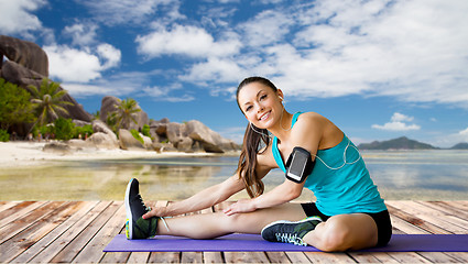 Image showing woman with smartphone stretching leg on mat