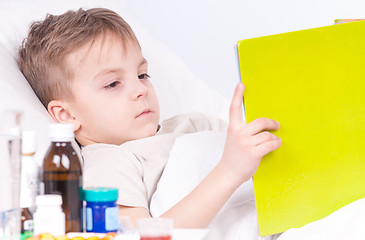 Image showing Sick boy in bed reading book
