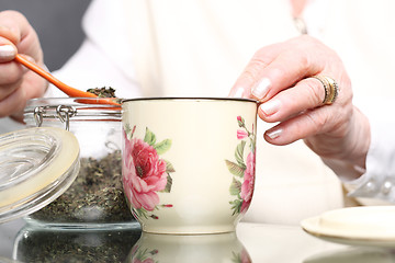 Image showing Grandma's herbs for colds. Brew of herbs, herbal medicine. Elderly woman burns herbs 