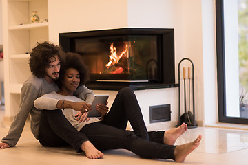 Image showing multiethnic couple using tablet computer on the floor