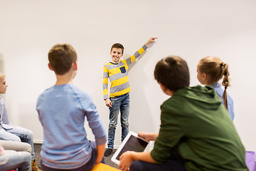 Image showing happy student boy showing something at white wall