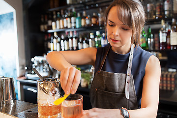 Image showing barmaid with glass and jug preparing cocktail