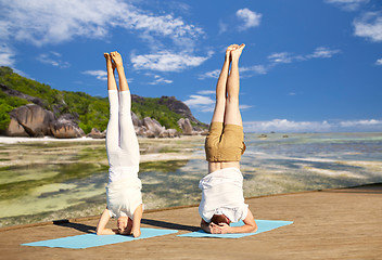 Image showing couple making yoga headstand on mat outdoors