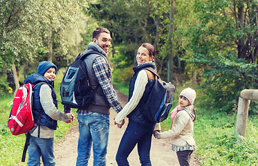 Image showing happy family with backpacks hiking in woods