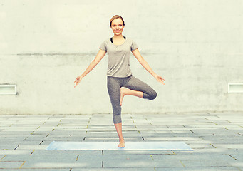 Image showing woman making yoga in tree pose on mat