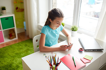 Image showing girl with smartphone distracting from homework