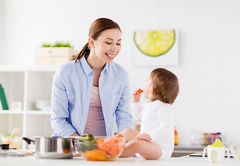 Image showing happy mother and baby eating at home kitchen