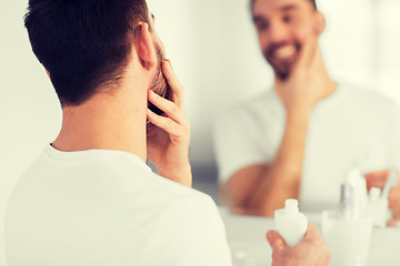 Image showing close up of man applying cream to face at bathroom