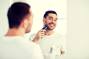 Image showing man shaving beard with trimmer at bathroom