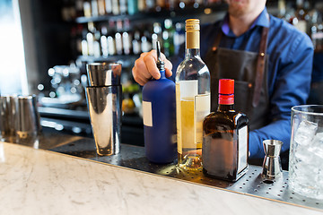 Image showing barman with shaker, alcohol and jigger at bar