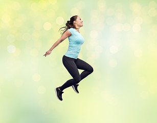 Image showing happy smiling sporty young woman jumping in air