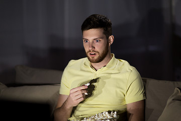 Image showing man watching tv and eating popcorn at night