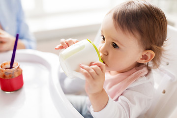 Image showing baby drinking from spout cup in highchair at home