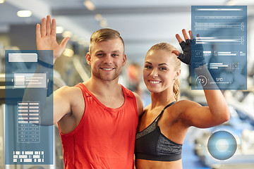 Image showing smiling man and woman waving hands in gym