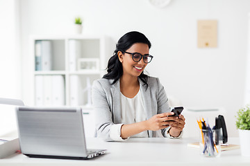 Image showing businesswoman with smartphone and laptop at office