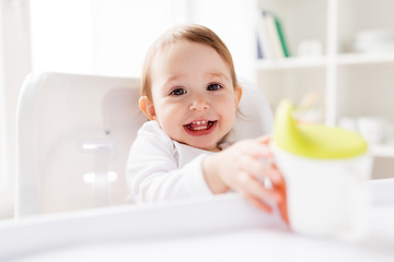 Image showing baby drinking from spout cup in highchair at home