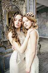 Image showing two pretty twin sister blond curly hairstyle girl in luxury house interior together, rich young people concept