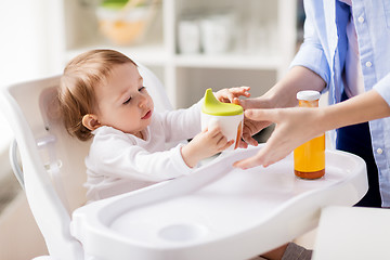 Image showing mother giving spout cup with juice to baby at home