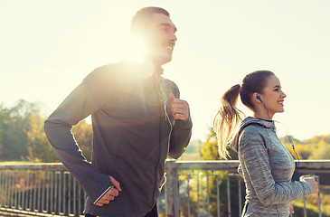 Image showing happy couple with earphones running outdoors