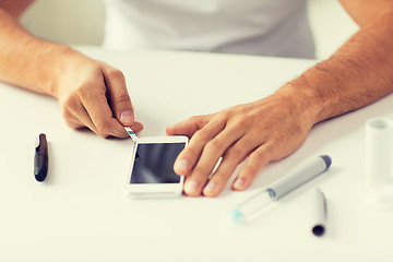 Image showing close up of man with smartphone making blood test