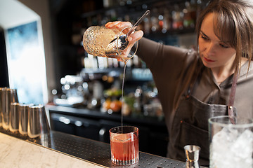 Image showing barmaid with glass and jug preparing cocktail