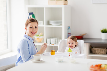 Image showing happy mother feeding baby with puree at home