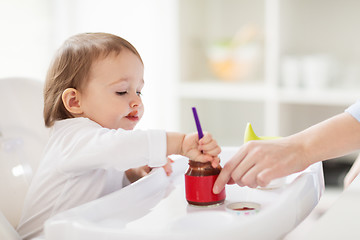 Image showing baby with spoon eating puree from jar at home