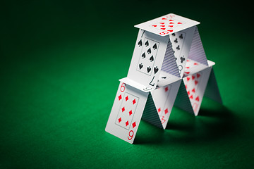 Image showing house of playing cards on green table cloth