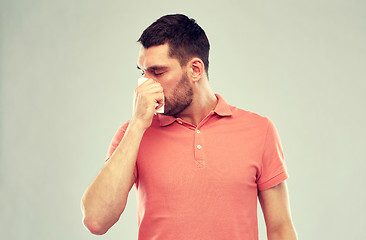 Image showing sick man with paper napkin blowing nose