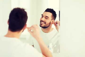 Image showing man cleaning ear with cotton swab at bathroom