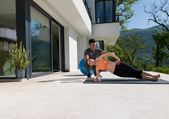 Image showing woman with personal trainer doing morning yoga exercises