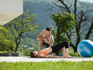 Image showing woman with personal trainer doing morning yoga exercises