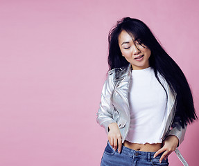 Image showing young pretty smiling asian korean girl wearing modern fashion clothers on pink background, lifestyle people concept 