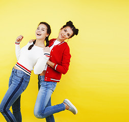 Image showing lifestyle people concept: two pretty young school teenage girls having fun happy smiling on yellow background 