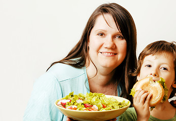 Image showing mature woman holding salad and little cute boy with hamburger te