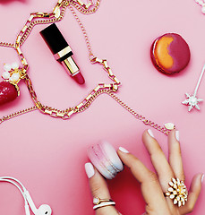 Image showing woman hands holding macaroons with lot of girl stuff on pink background, girls accessories concept 