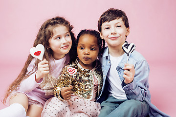 Image showing lifestyle people concept: diverse nation children playing together, caucasian boy with african little girl holding candy happy smiling 