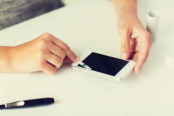 Image showing close up of woman with smartphone doing blood test