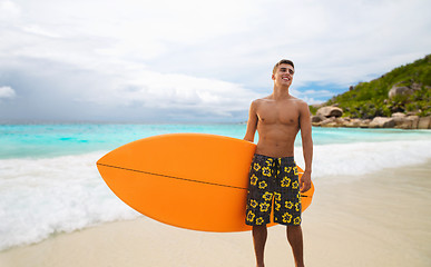 Image showing smiling young man with surfboard on summer beach