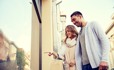 Image showing happy couple with shopping bags at shop window