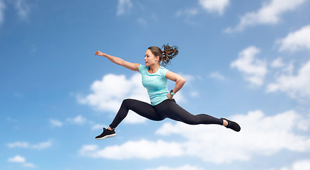 Image showing happy sporty young woman jumping in fighting pose