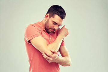 Image showing unhappy man suffering from pain in hand