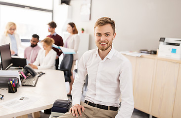 Image showing happy young man over creative team in office